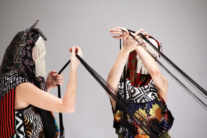Artistic performers in masks with black thread.