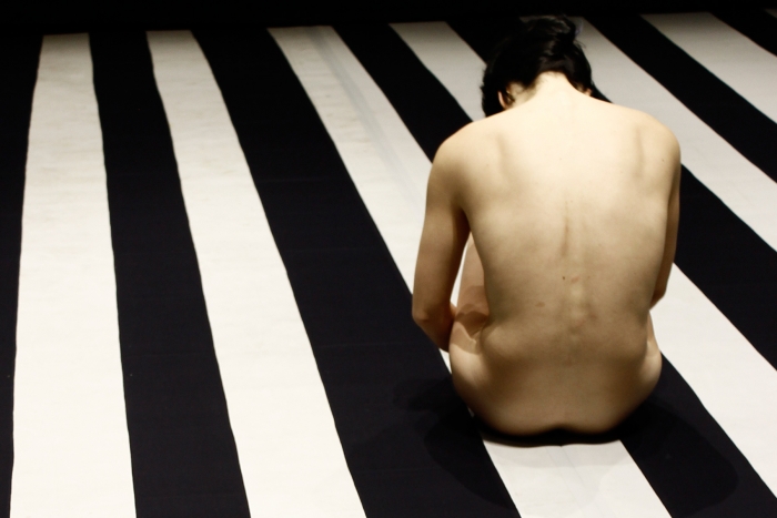 Person sitting on black and white striped floor.