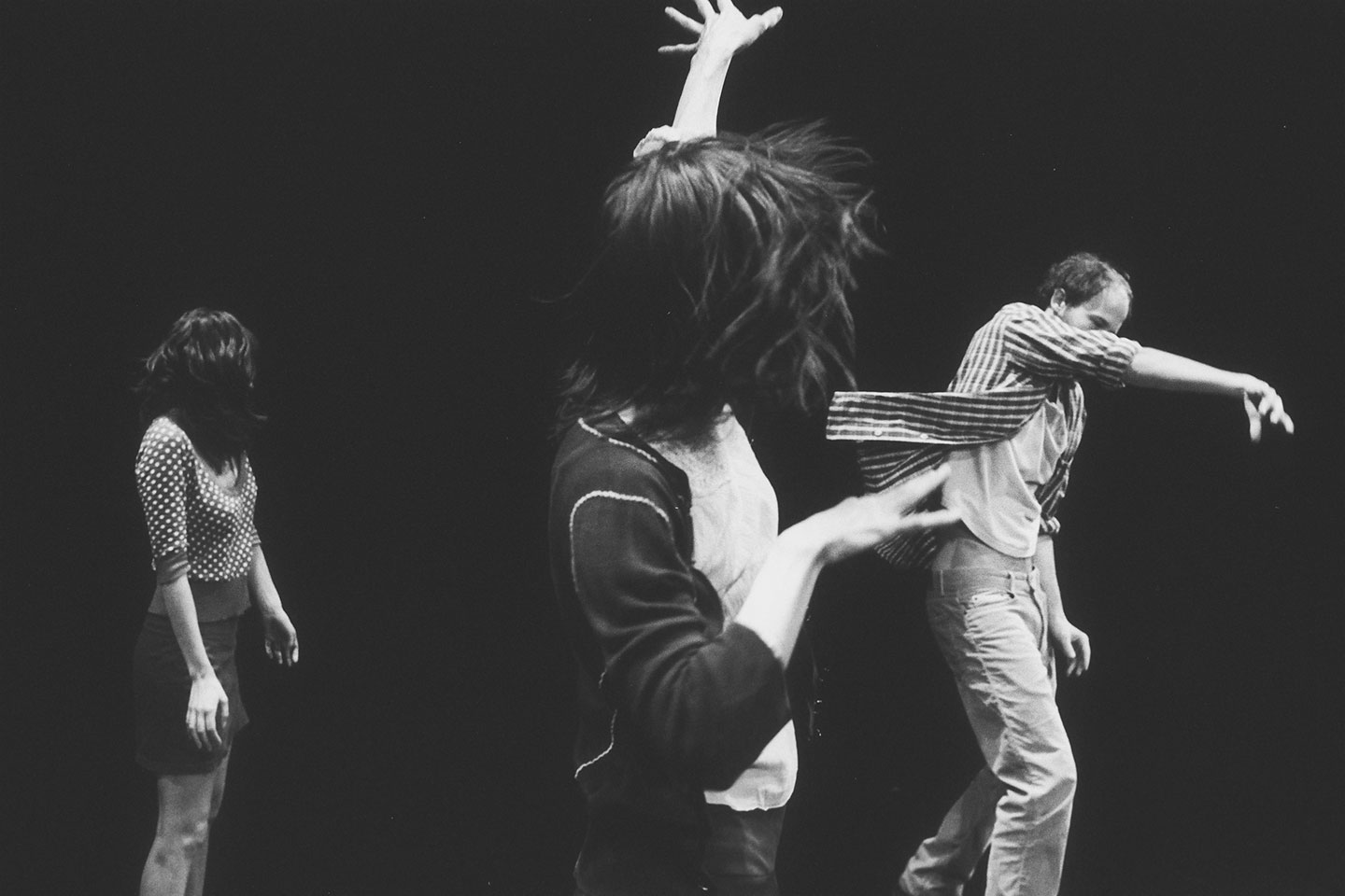 Three people dancing on stage, black and white photo.