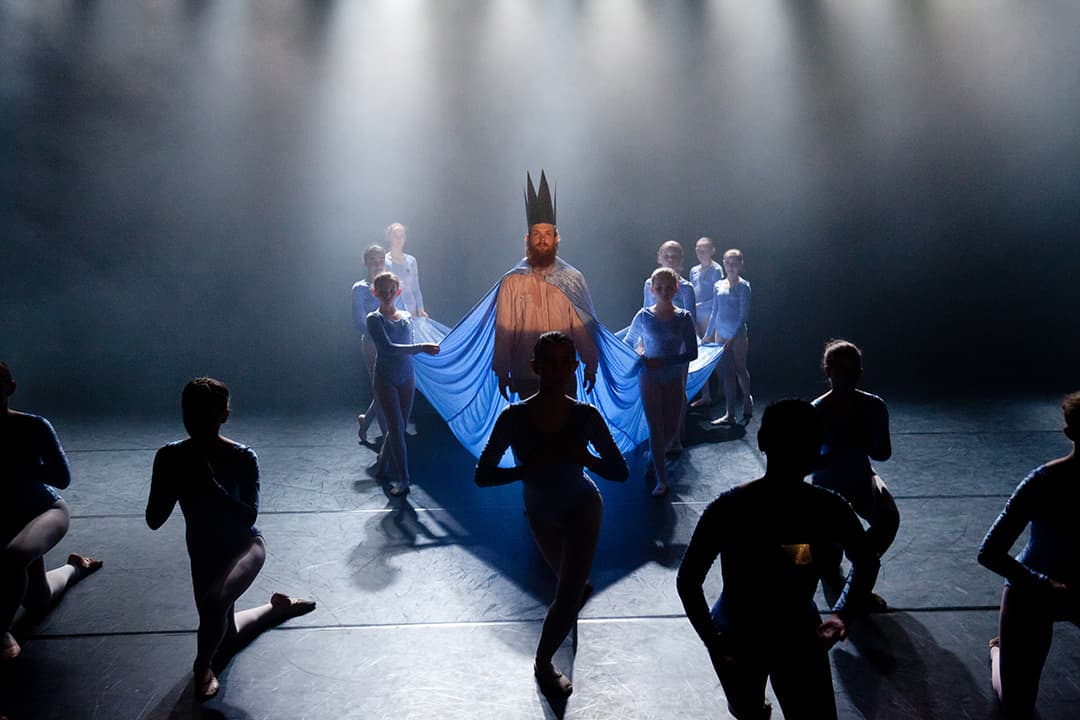 Dancers performing with blue fabric and crown.