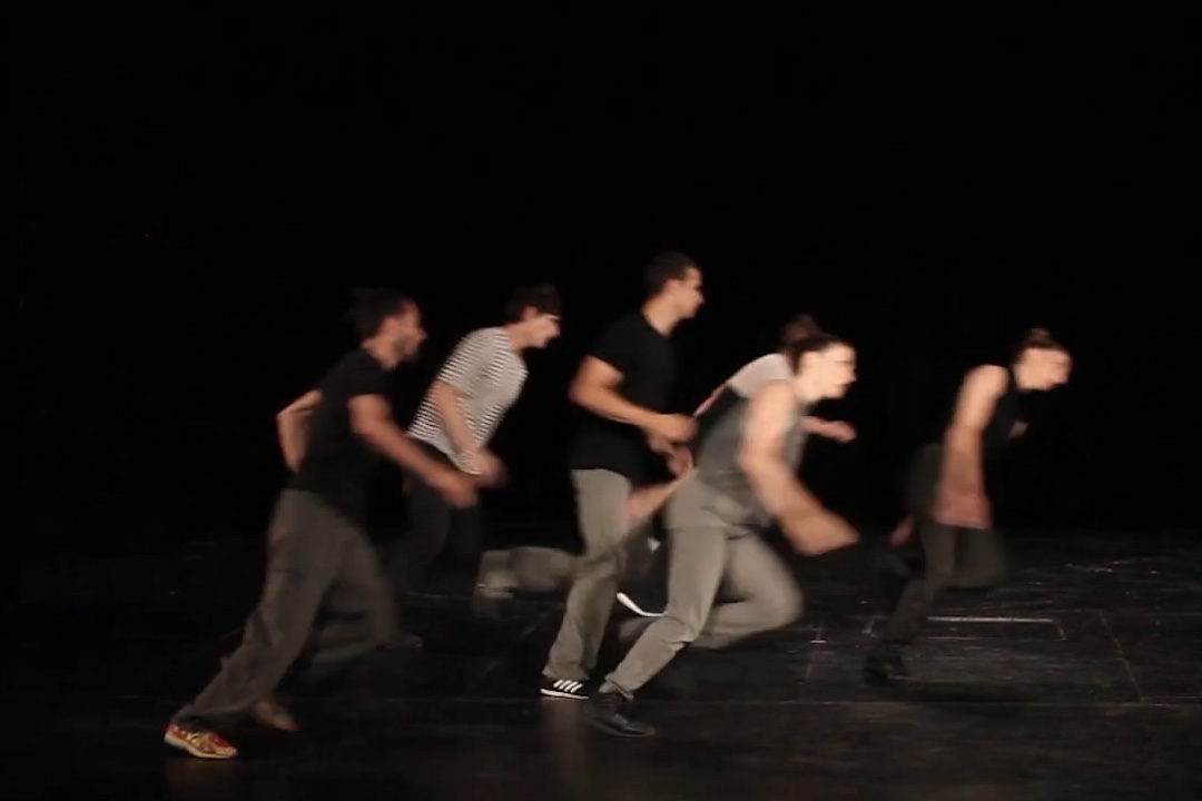 Group of performers running on a dark stage.