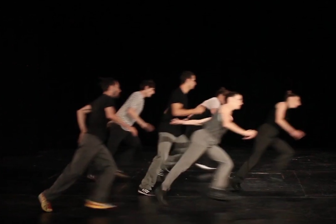Dancers moving in synchronised group formation on stage.