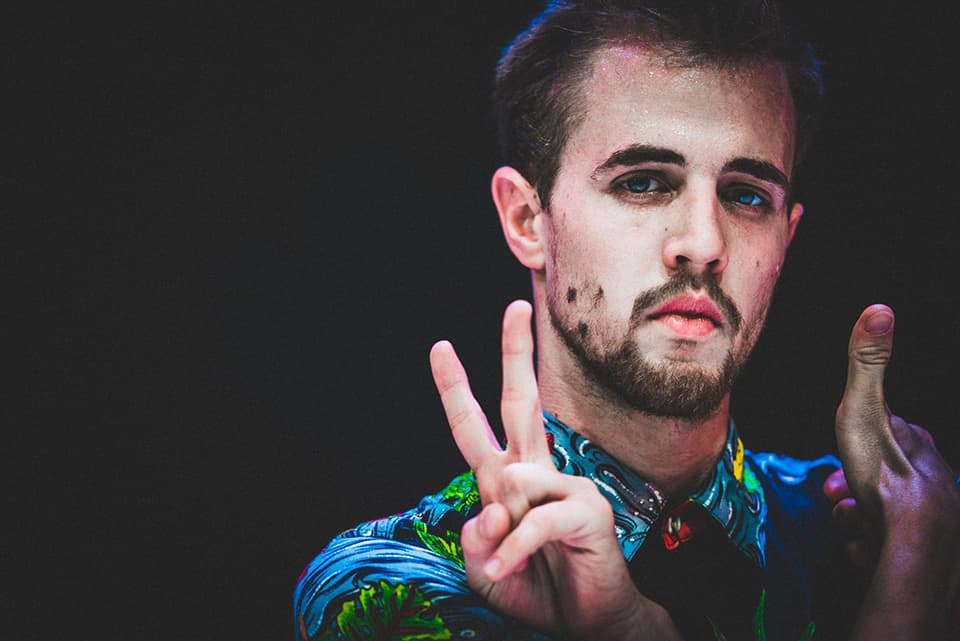 Man making peace sign gesture, colourful shirt.