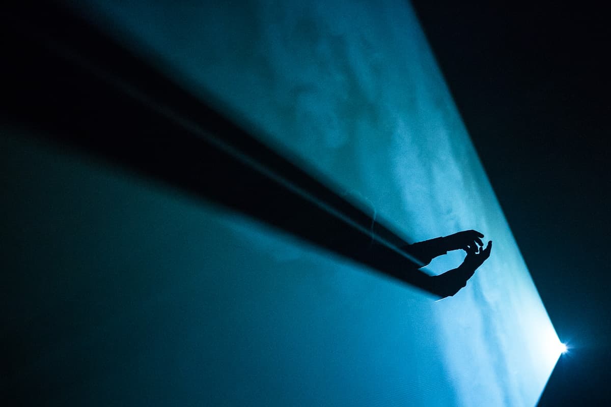 Silhouette of hand in blue light beam.