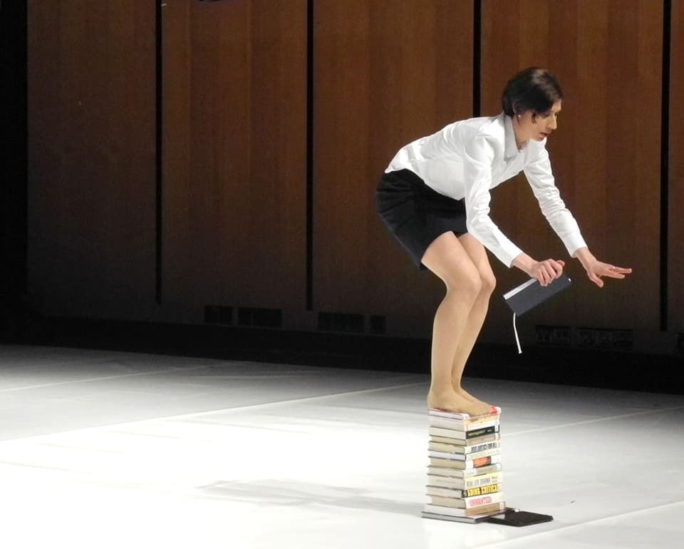 Woman balancing on a stack of books.