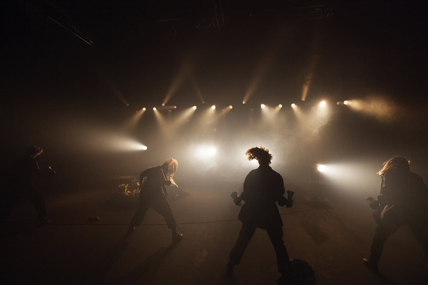 Dancers perform energetically under dramatic stage lighting.