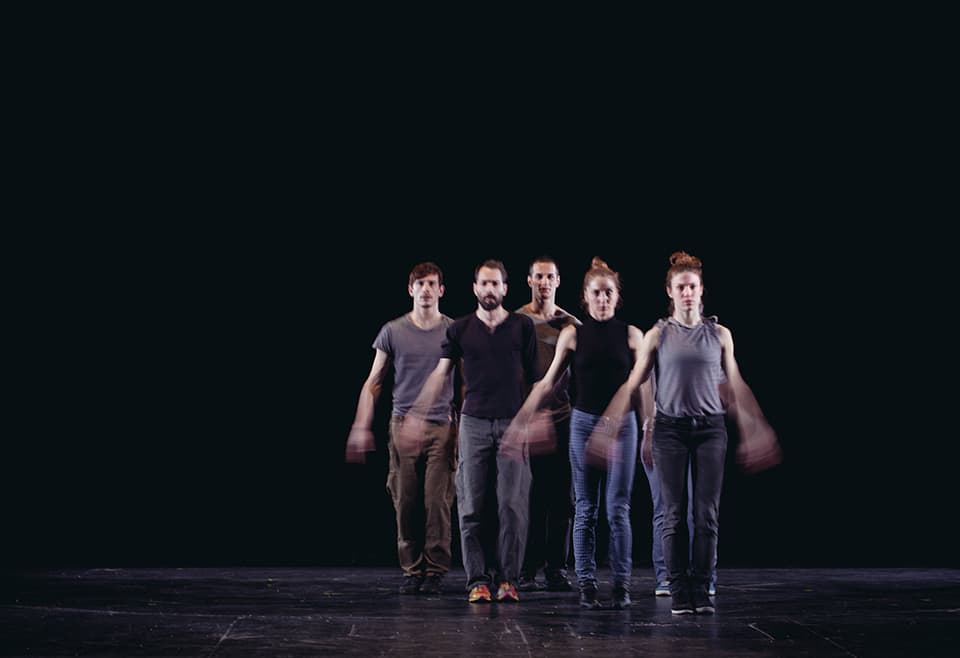 Five dancers performing a synchronised routine on stage.
