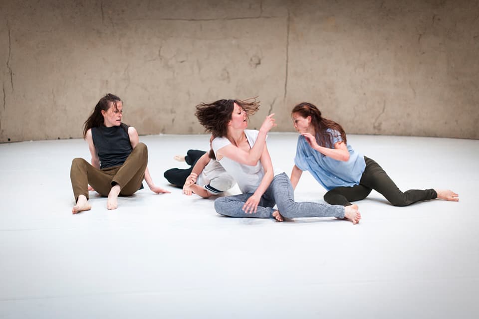 Four women performing modern dance on stage.