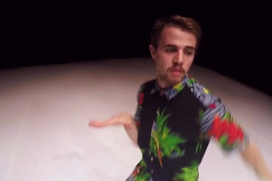 Person dancing in colourful floral shirt on stage.