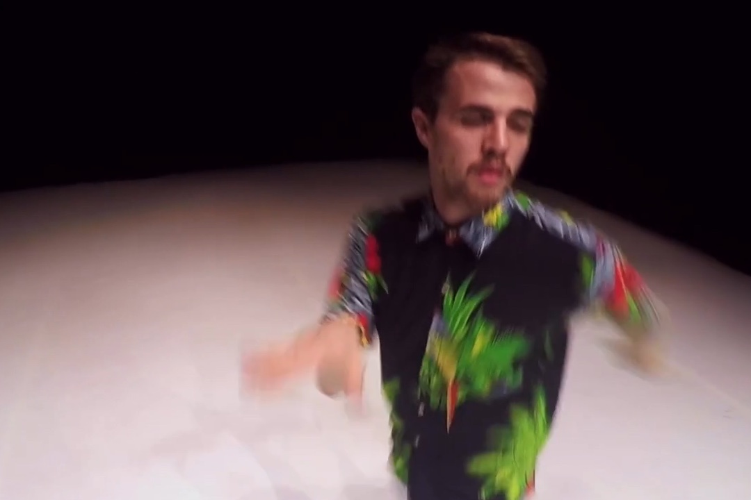 Man dancing on stage in floral shirt.