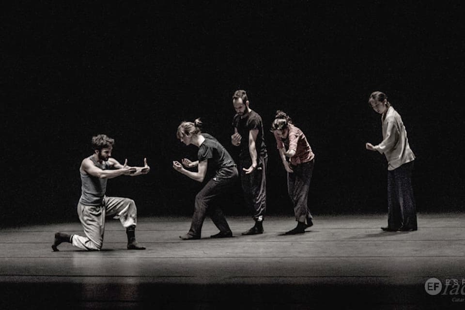 Five dancers perform expressive choreography on stage.