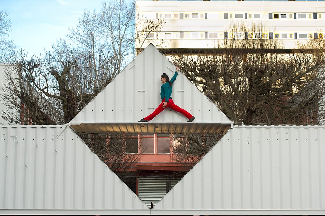 Person performs split on triangular rooftop structure.
