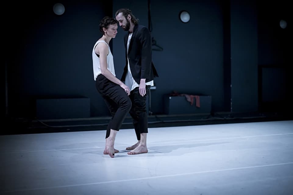 Two dancers perform barefoot on stage.