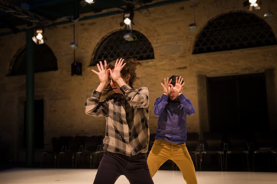 Two dancers performing expressive movements on stage.