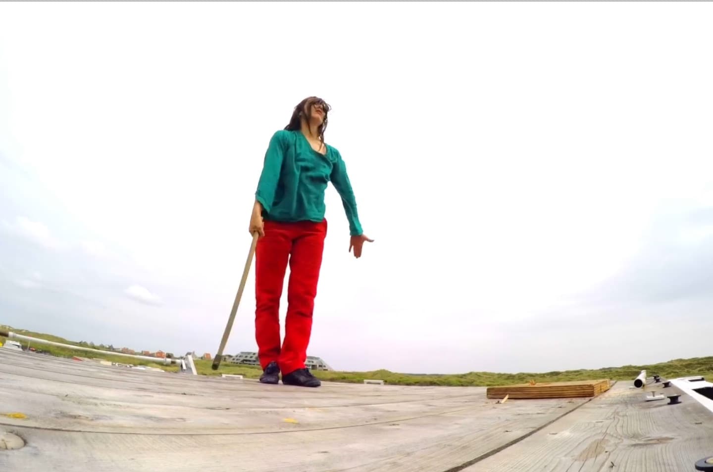 Person with stick standing on wooden platform outdoors.
