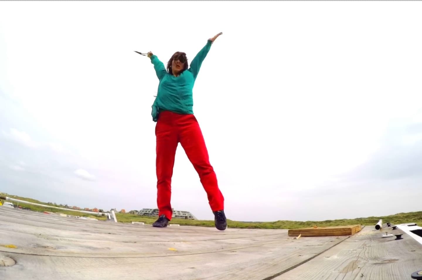 Person jumping energetically on wooden deck outdoors.