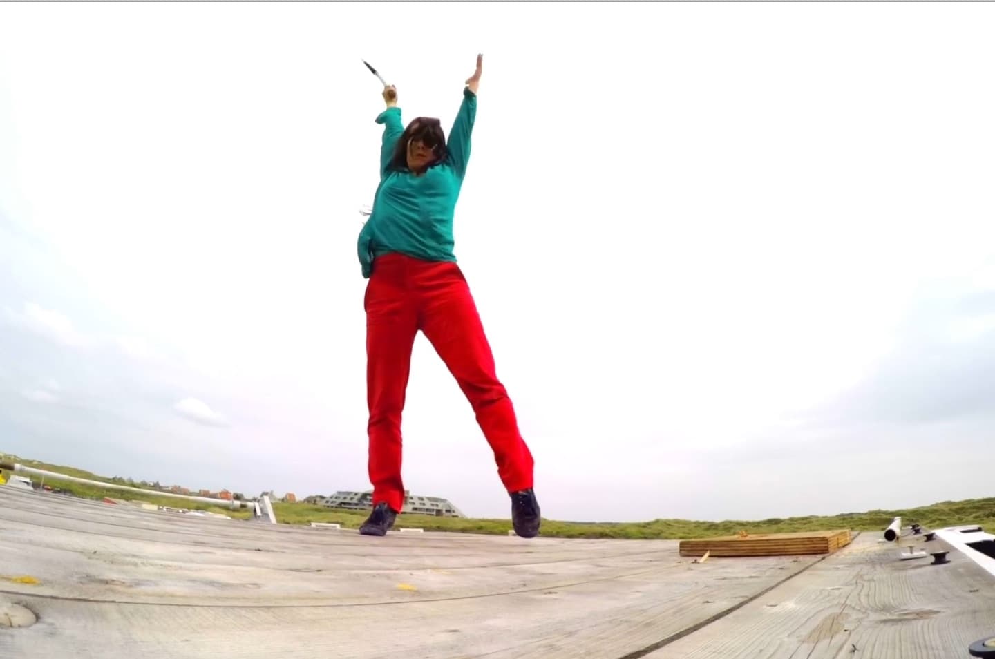 Person jumping energetically on wooden deck outdoors.