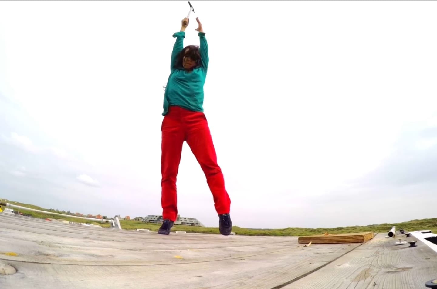 Person swinging hammer outdoors on wooden platform.