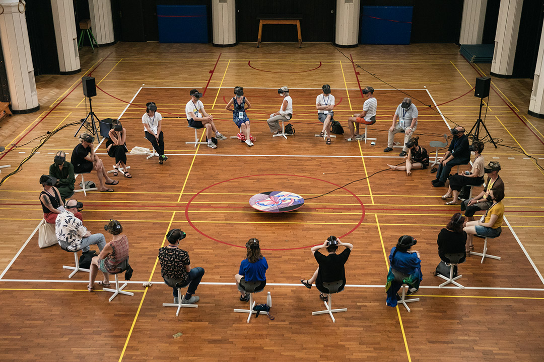 People seated in circle, wearing virtual reality headsets.