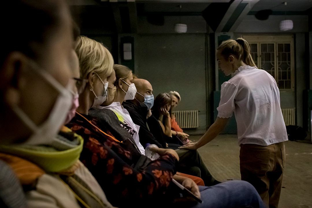 Masked audience seated indoors during performance.