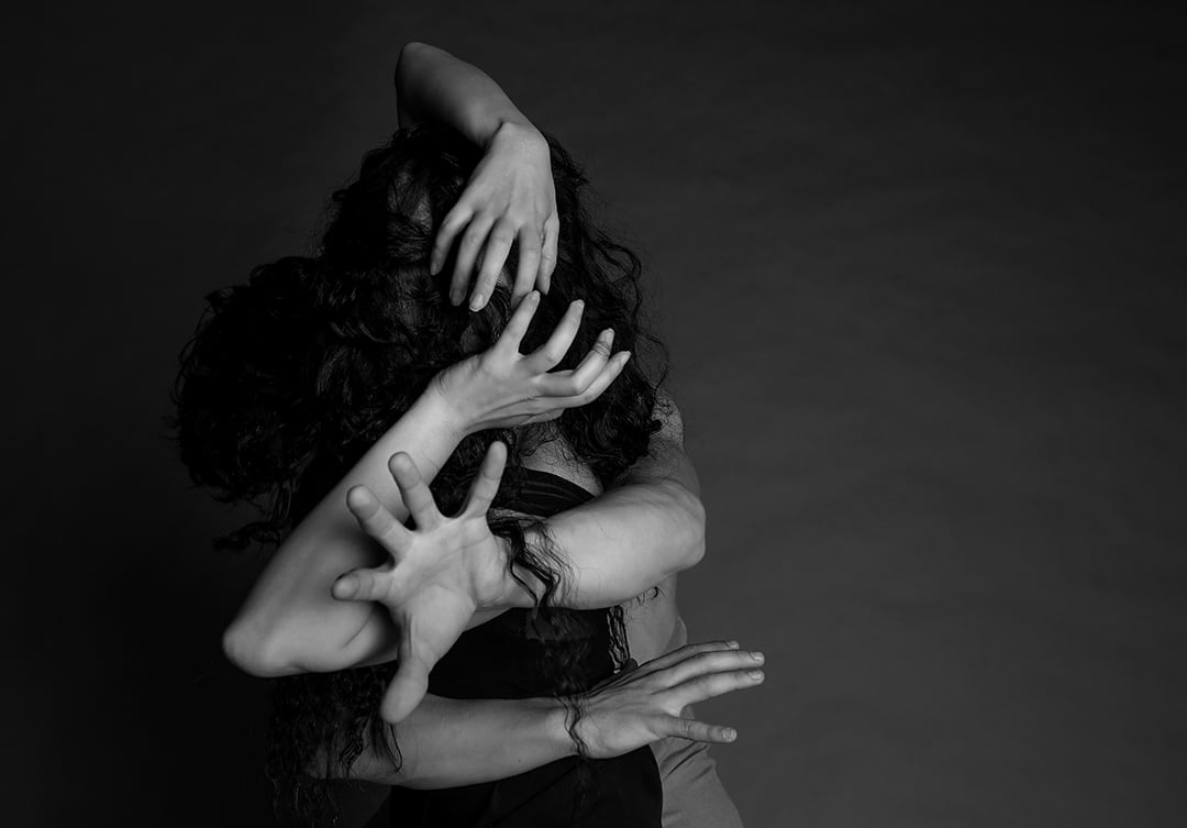 Abstract dance pose with overlapping hands in black-and-white.