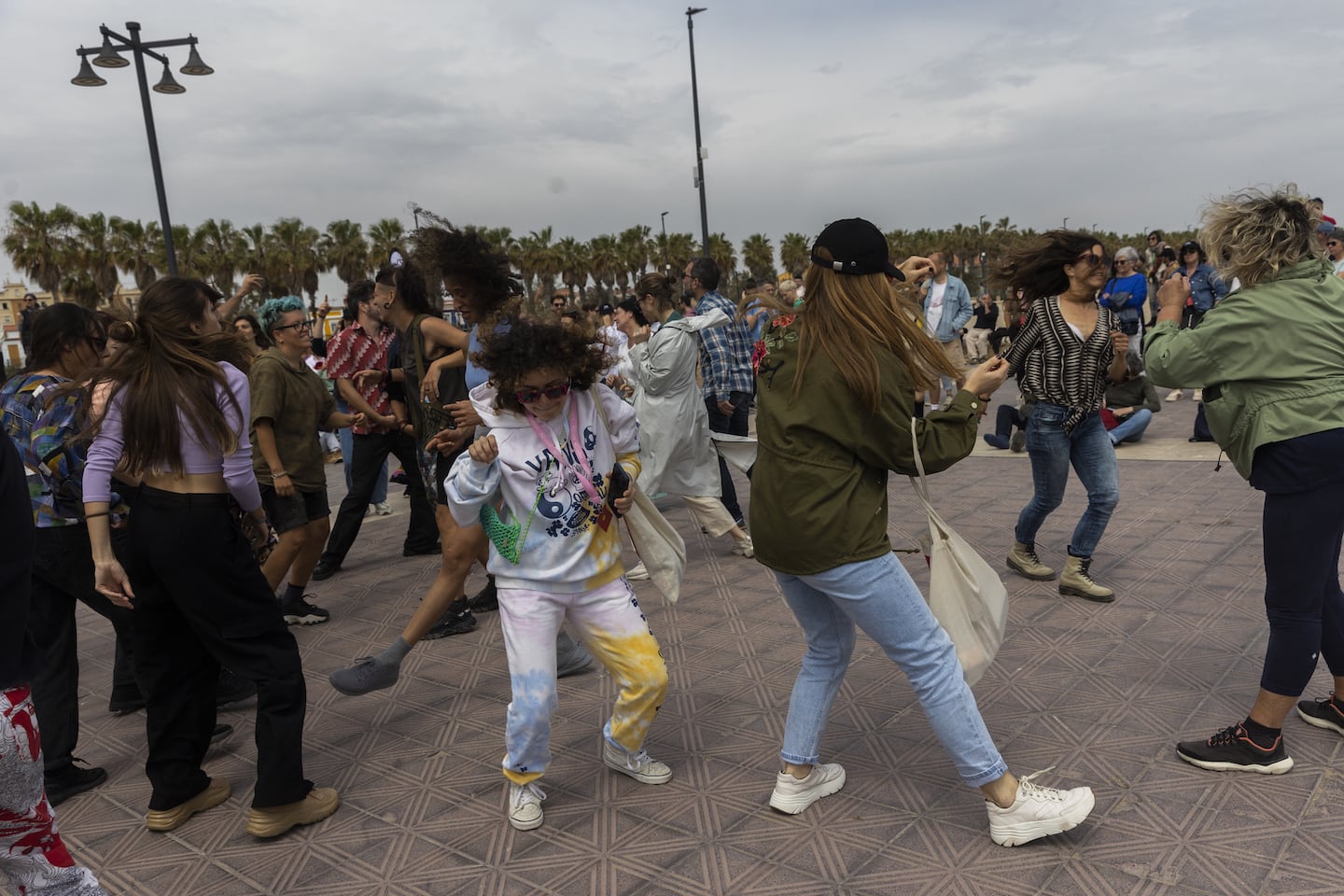 A crowded group of people and passers-by bopping in the open air on a paved promenade