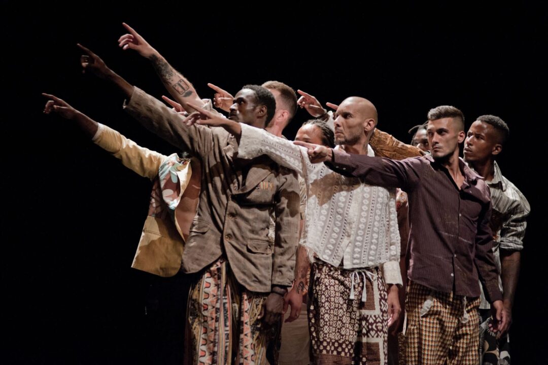 Group of dancers pointing dramatically on stage.