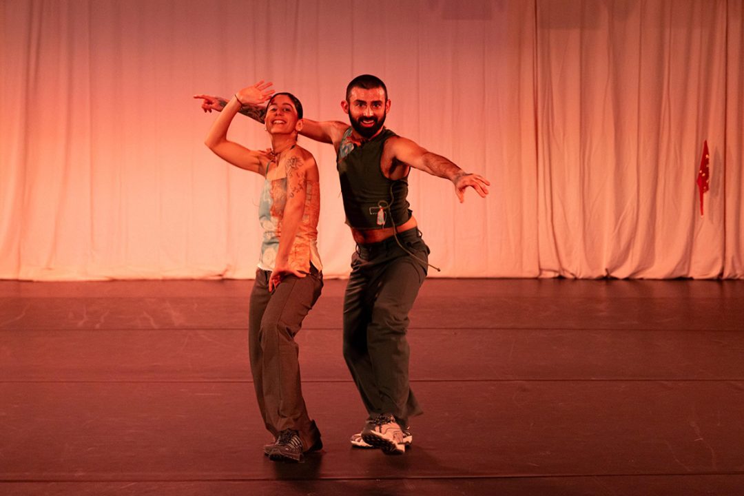 Two dancers performing on stage, expressive movements.