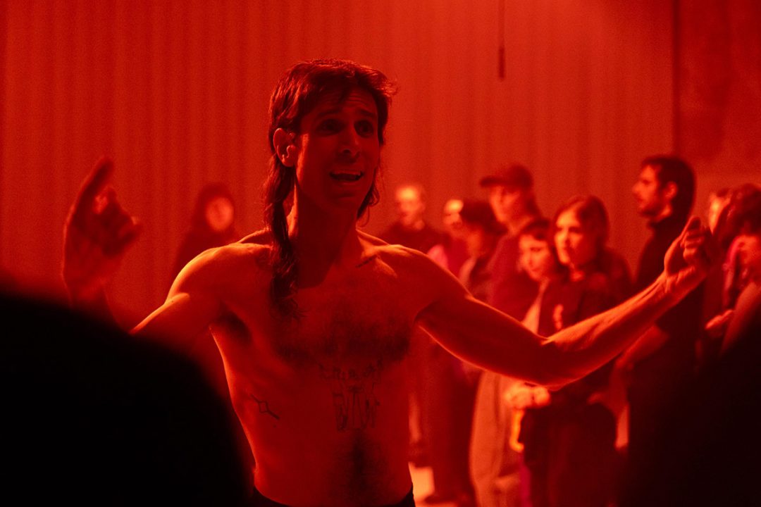 Person performing passionately in red lighting.