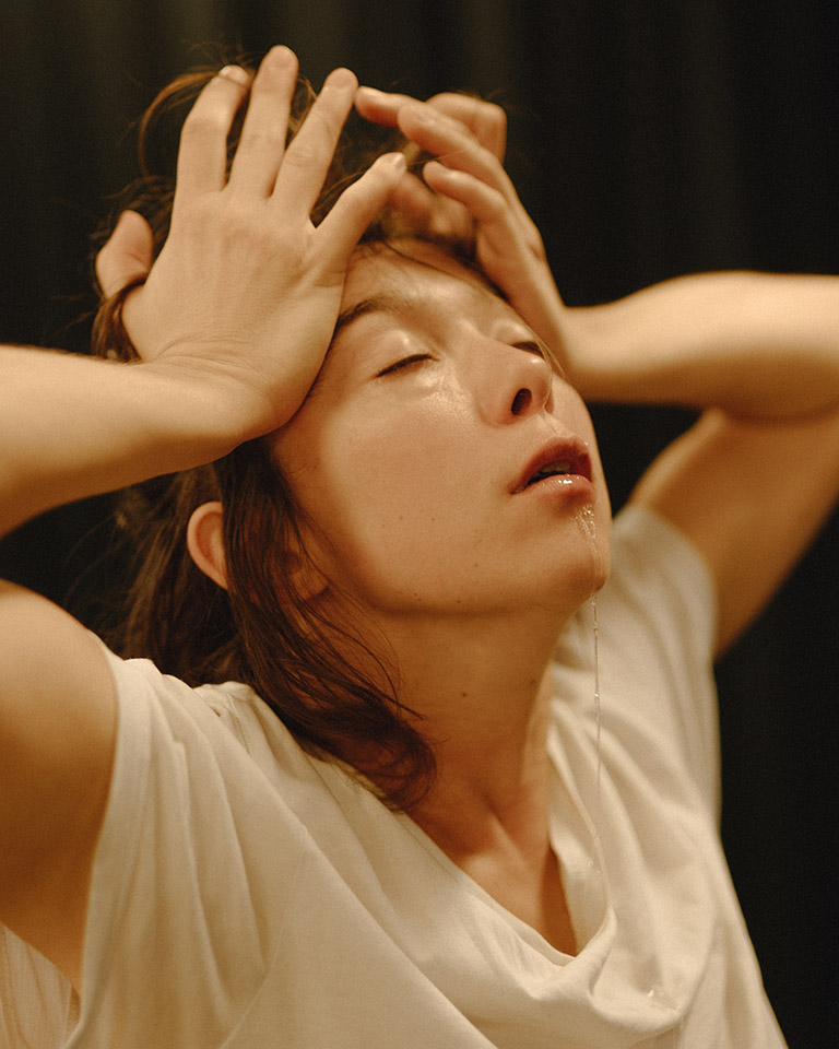 Person expressing emotion, hands on head, eyes closed.