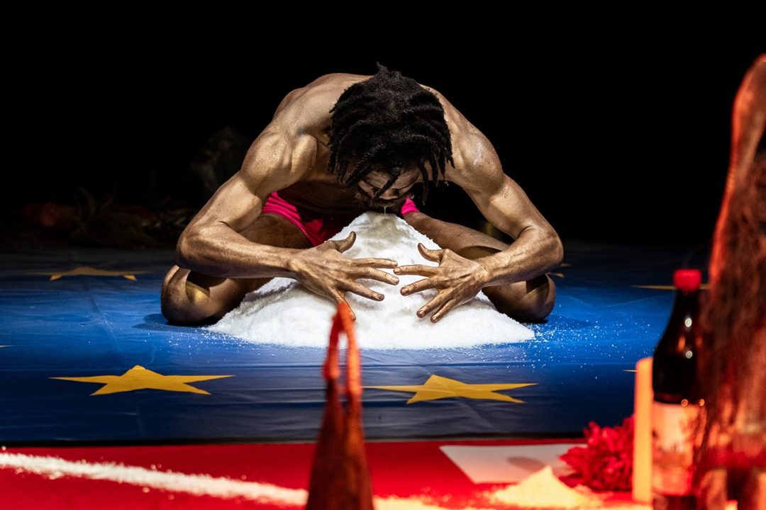 Performer interacting with salt pile on stage.