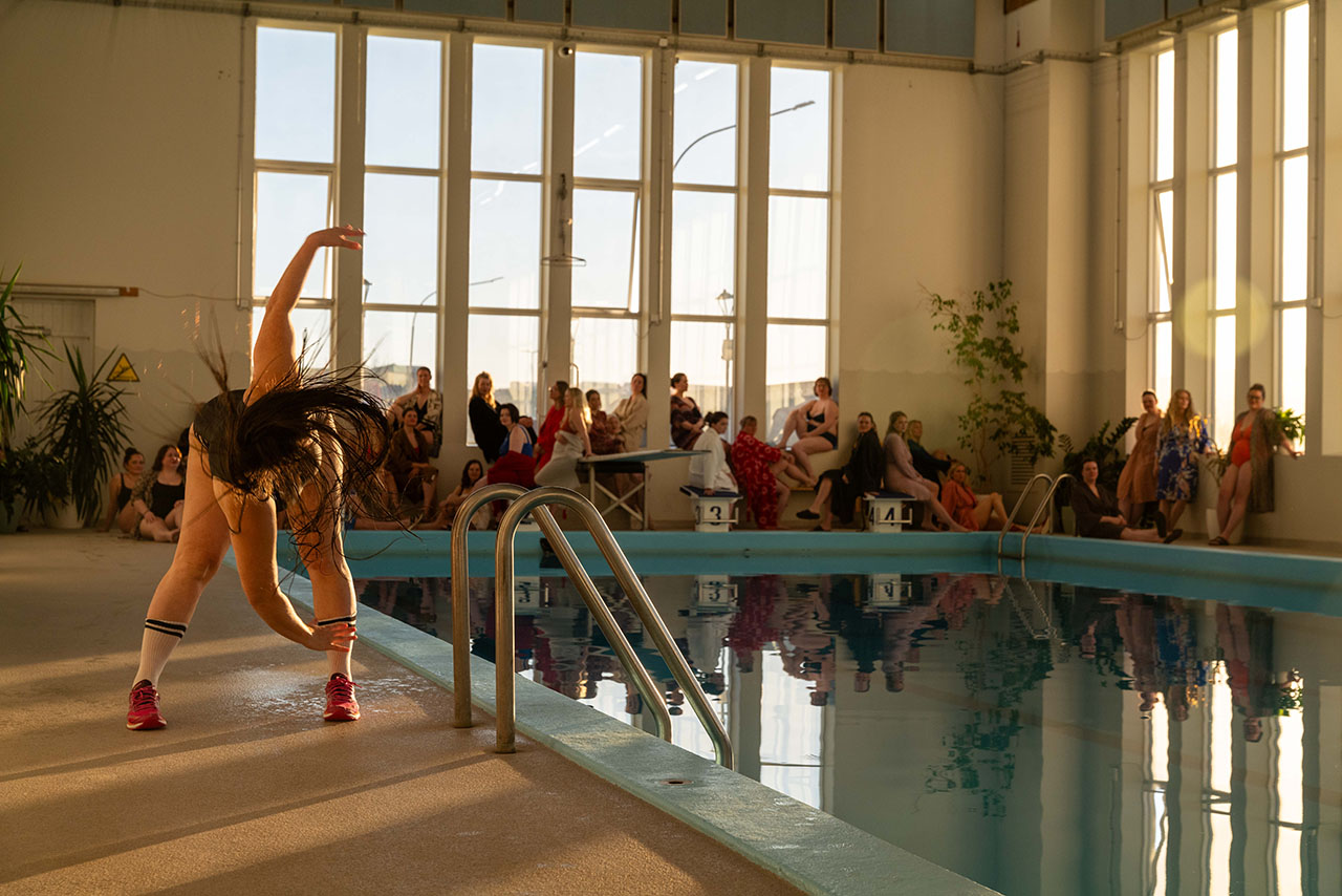 Woman performing beside indoor swimming pool audience