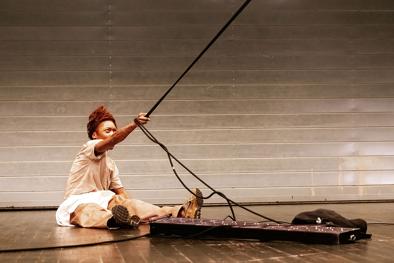 A lone performer commands the stage with a single sweeping gesture. The tension of the cable mirrors the intensity of the moment.