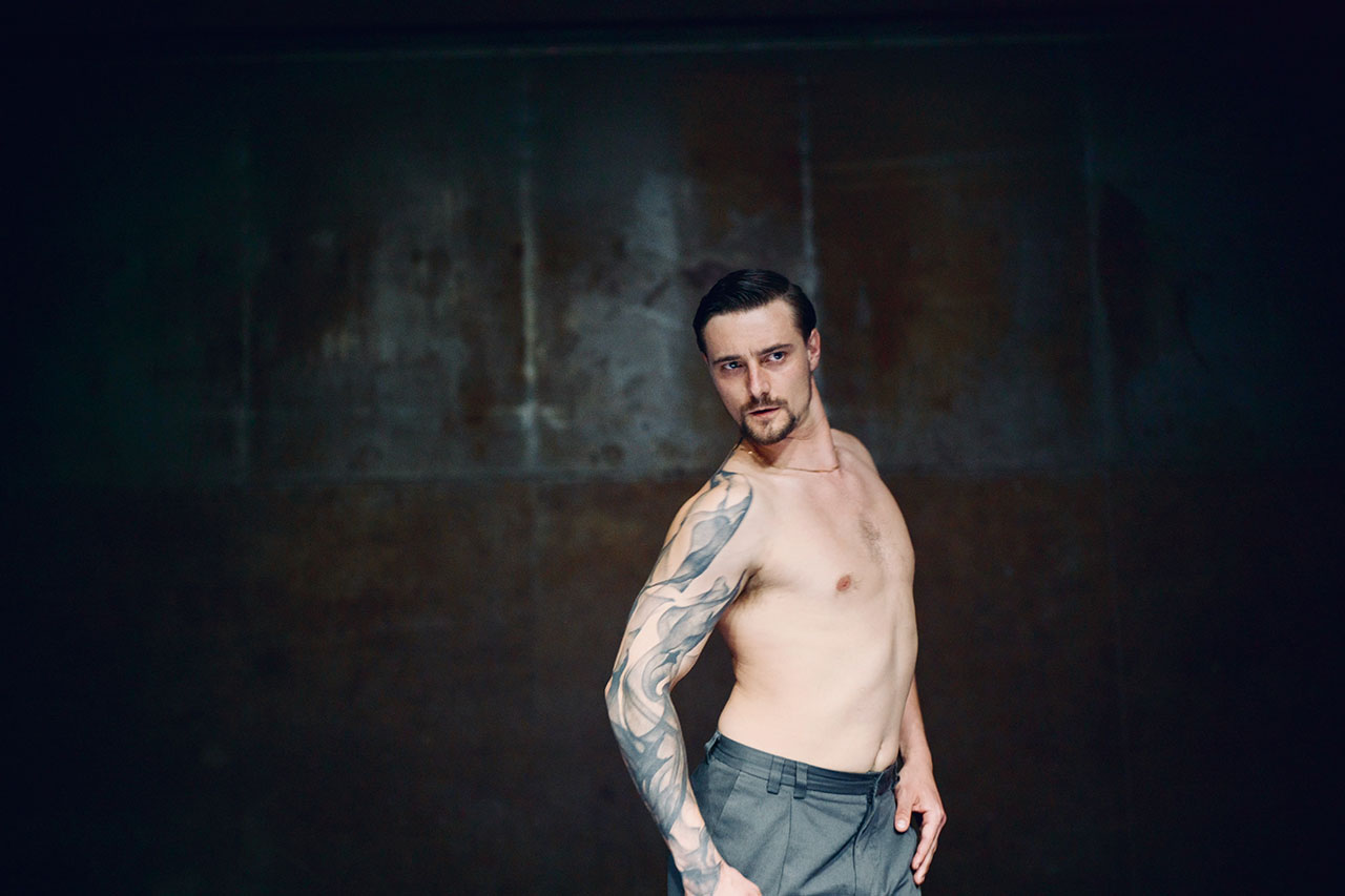 Shirtless man with tattooed arm in dark room