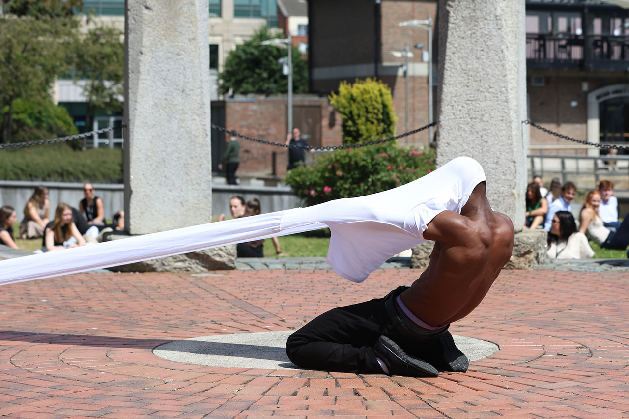 A striking outdoor performance unfolds in a city square. The artist uses fabric and movement to create a powerful visual moment.