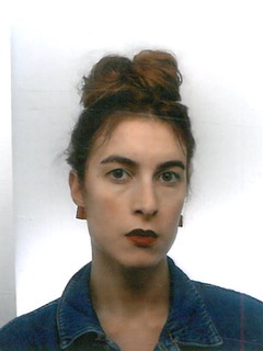 A striking portrait of a woman with her hair in a bun. Her calm expression and dark lipstick create a bold, modern look.