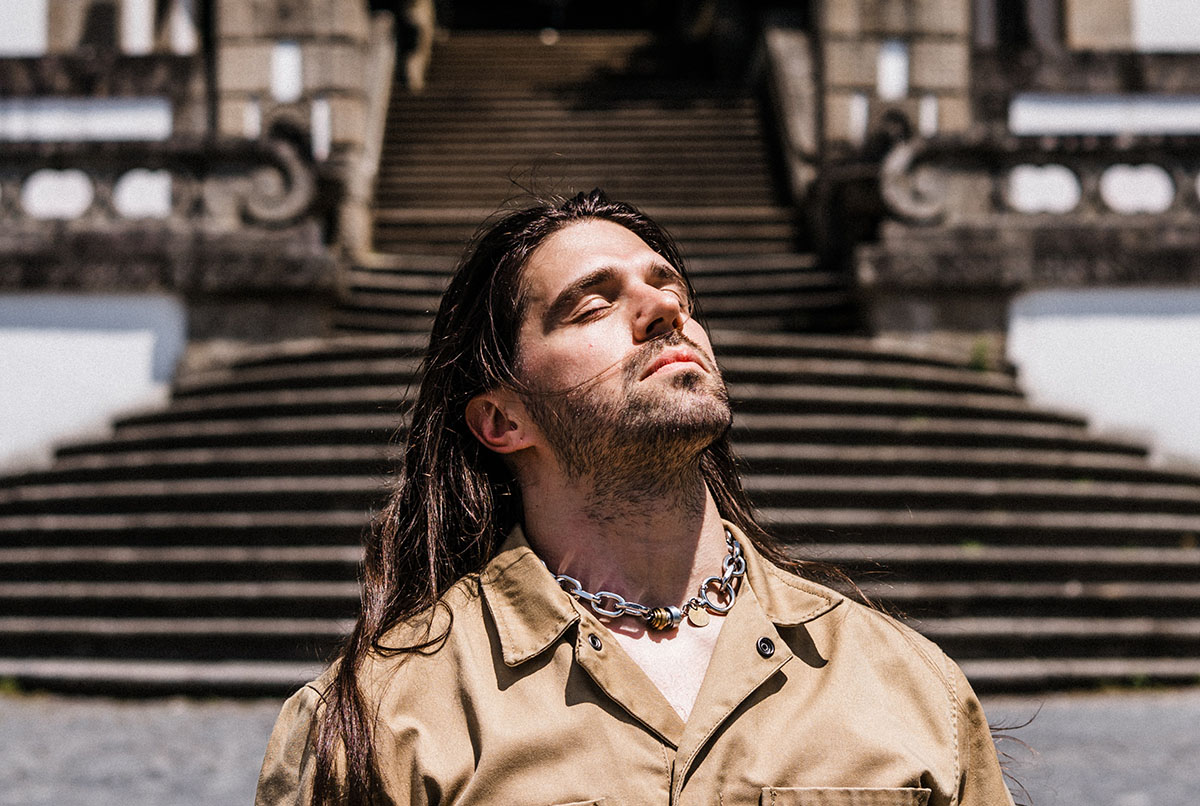 Man with long hair before stone steps