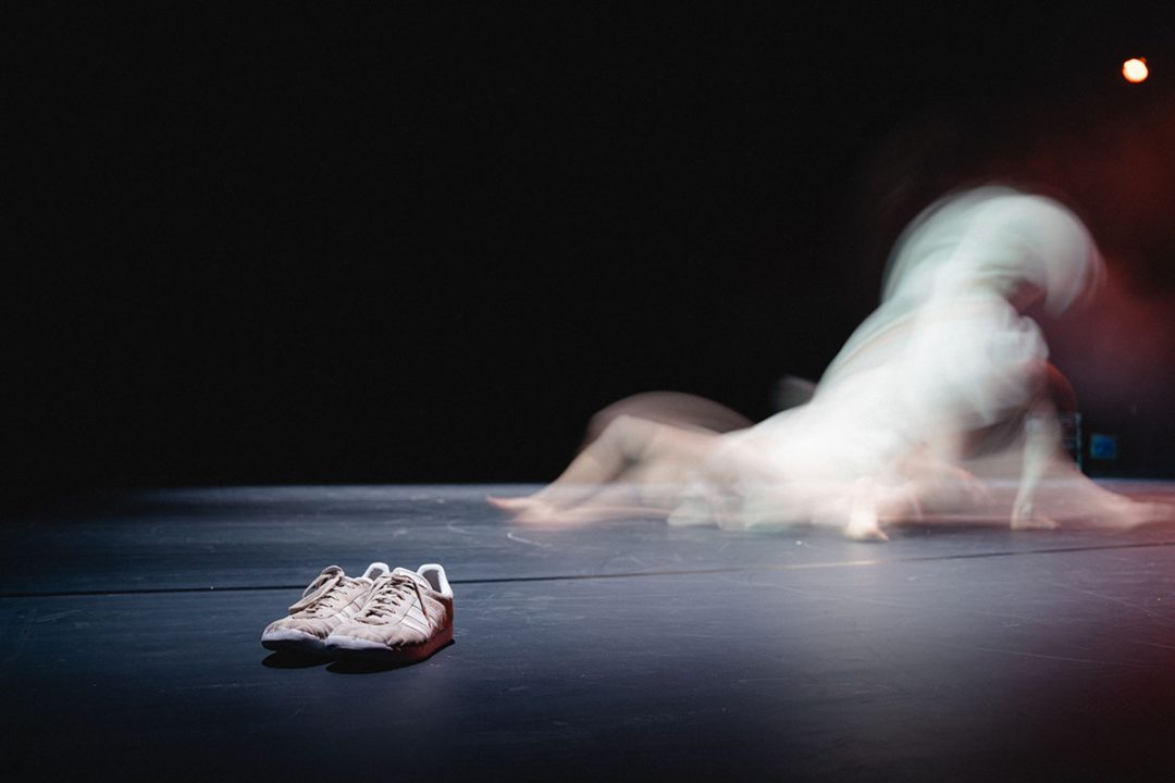 White trainers on stage with blurred dancer