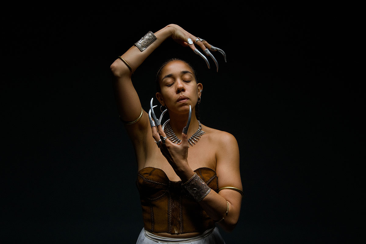 A striking studio portrait capturing elegance and edge. The model’s metallic claws and sculptural pose create a bold, dramatic statement.