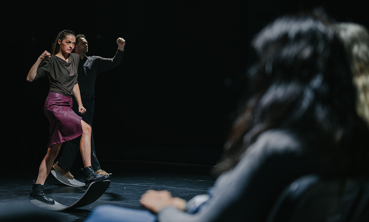 Two dancers balancing on curved boards on stage