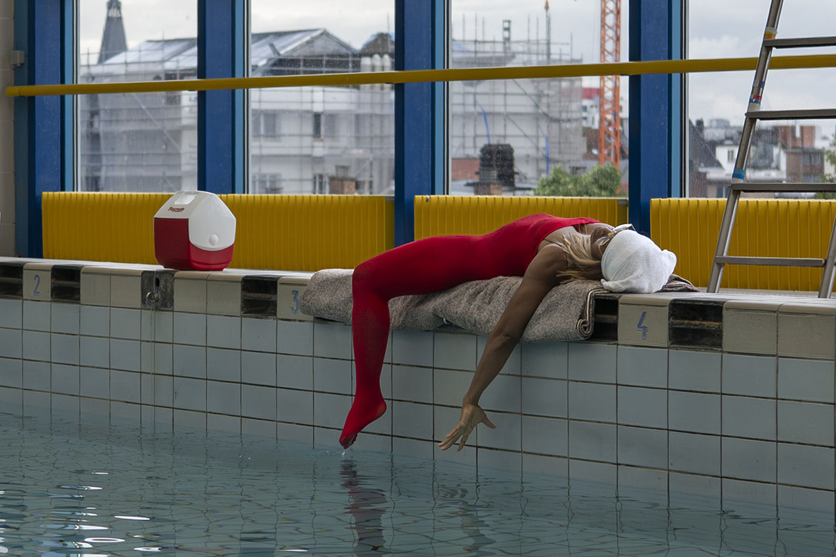 Person in red outfit lying by indoor pool