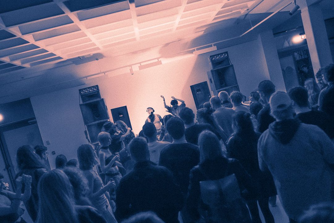 Crowd watching DJ perform at indoor venue