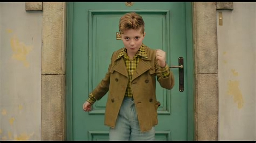 Young boy posing confidently in front of green door