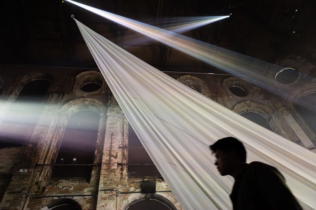 Silhouetted figure beneath dramatic light and fabric installation