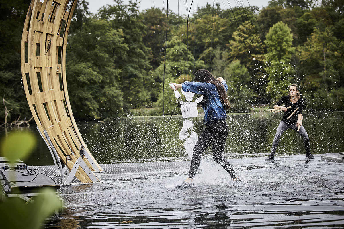 Two people splashing water beside wooden structure