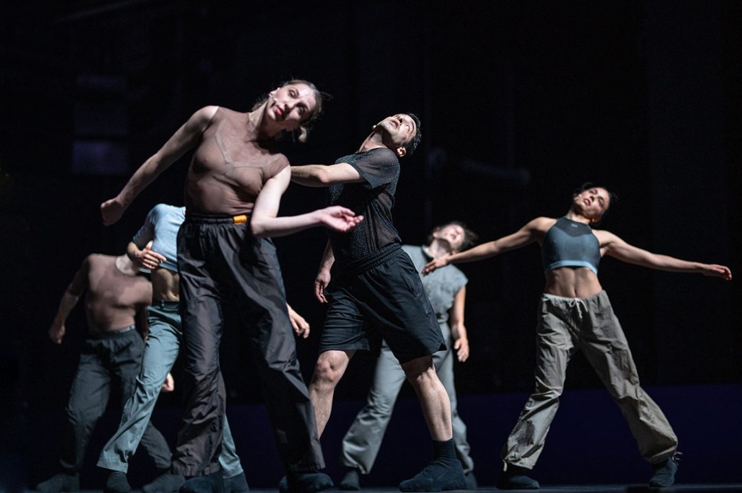 Contemporary dancers performing on dark theatre stage