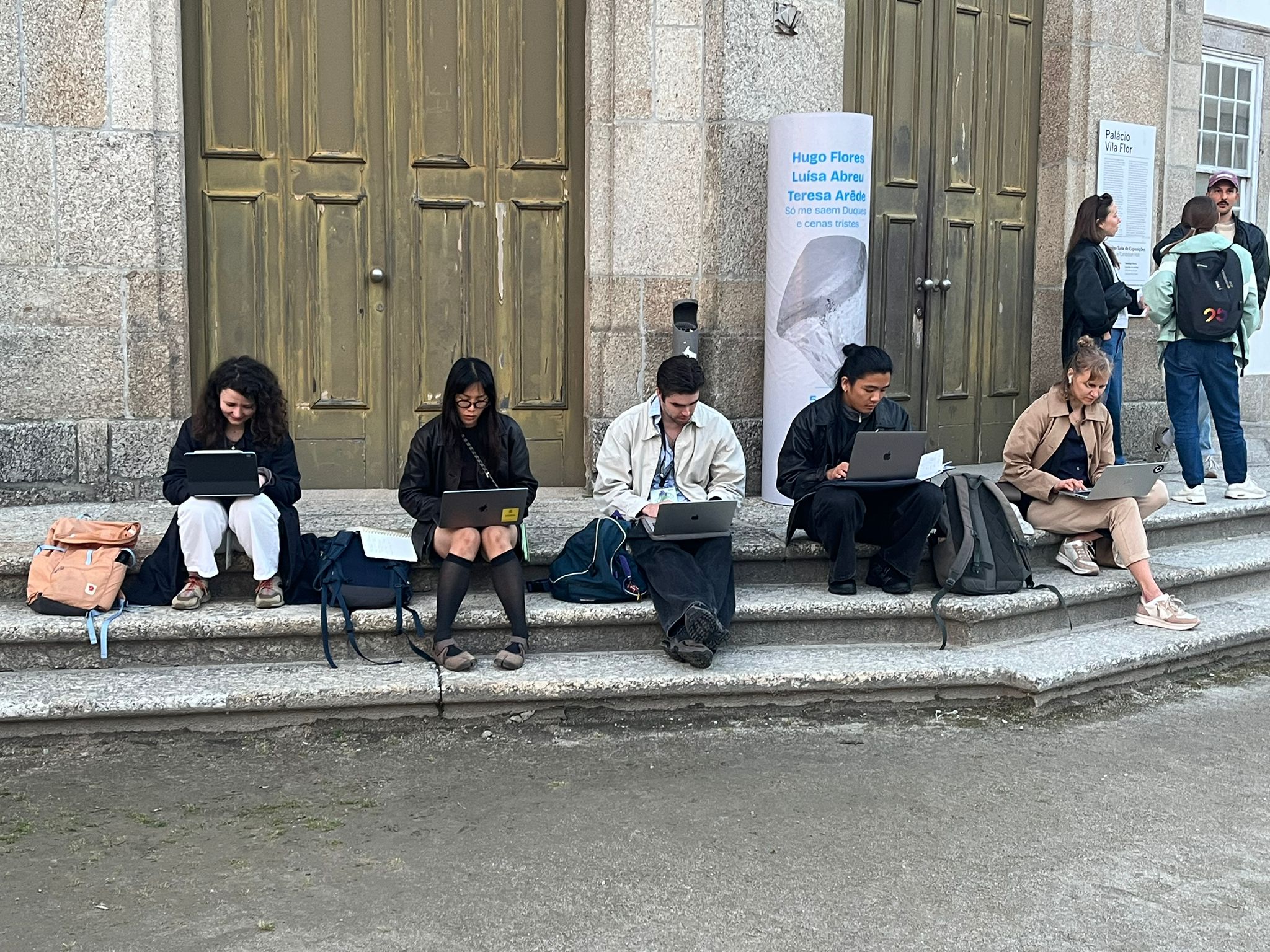 Students working on laptops outside historic building