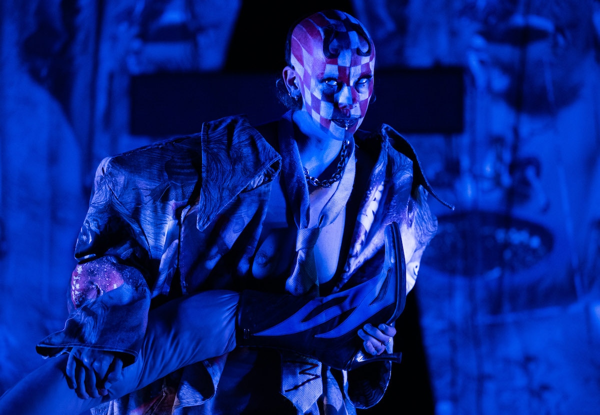 Performer with geometric face paint under blue lighting