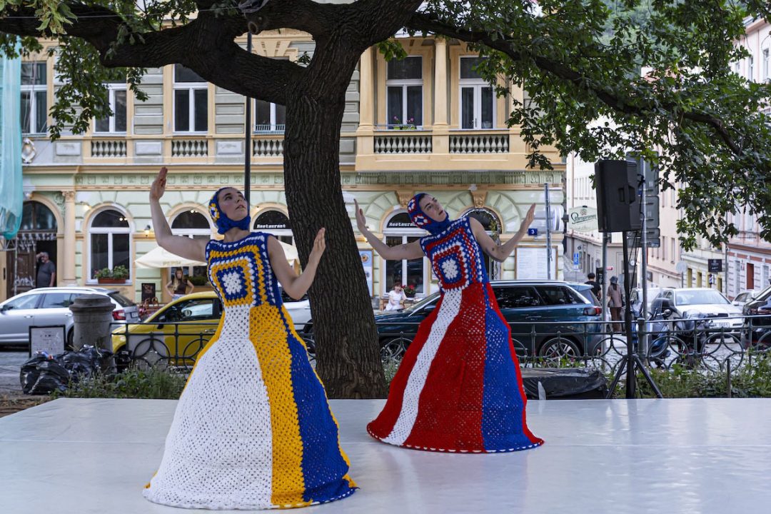 Two dancers in colourful crocheted dresses outdoors