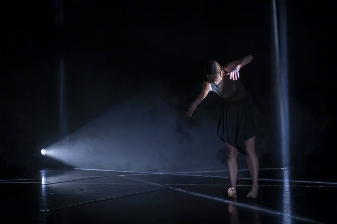 Contemporary dancer performing under dramatic stage spotlight